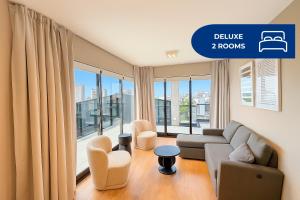 a living room with a couch and chairs and large windows at Live Belgrano Boutique Apartments in Buenos Aires