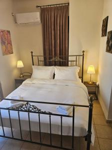 a bedroom with a bed with white sheets and a window at Amfitrion on the Town in Gythio