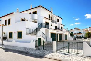 a white house with green doors and a fence at Apartamento Sunrise in Altura