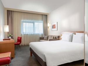 a hotel room with a large white bed and a chair at Novotel Gaziantep in Gaziantep