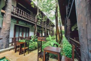 a row of wooden tables and chairs on a building at Treasure Heritage Luang Prabang Hotel in Luang Prabang