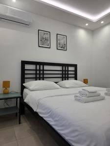 a bedroom with a bed with white sheets and a table at Sunset Apartment in Kotor