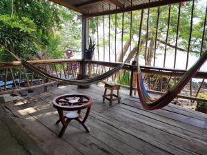 a hammock on a porch with a chair and a table at Rocks Beach in Balgue
