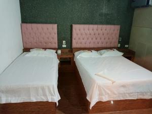 two beds in a room with white sheets and pink headboards at HOTEL FLORES LUCXON, ca in Caracas