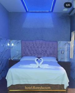 a bedroom with a bed with a purple head board at HOTEL FLORES LUCXON, ca in Caracas