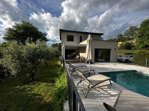 a patio with a chair and an umbrella next to a pool at villa des gorges in Vagnas