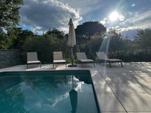 a swimming pool with two chairs and an umbrella at villa des gorges in Vagnas