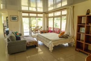 a bedroom with a bed and a chair and a window at Fare Faaroa Lodge in Taputapuapea