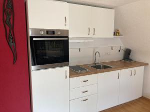 a small kitchen with white cabinets and a sink at RoDo Balcony - 2 Zimmer Apartment mit 1 Schlafzimmer & Balkon in Kirchheim unter Teck