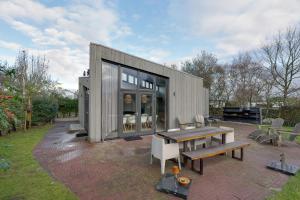 a small gray house with a picnic table and benches at Knookborst in Hollum
