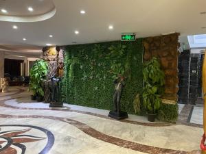 a lobby with a green wall with plants and a statue at Verssailles Al Manar Hotel in Cairo