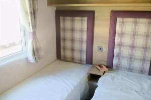a bedroom with two beds and a window at Spacious Caravan - Durdle Door Holiday Park in West Lulworth