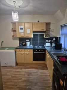 a kitchen with wooden cabinets and a black appliance at Beach Next Door Flat Retreat and Free Parking in Margate +6 photos
