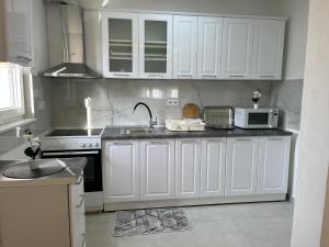 a kitchen with white cabinets and a sink and a microwave at Al Noor Villa Ilidža in Ilidža