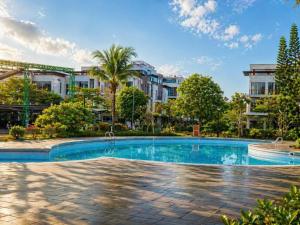 a swimming pool with trees and buildings in the background at Bareka Hotel in Phú Quốc