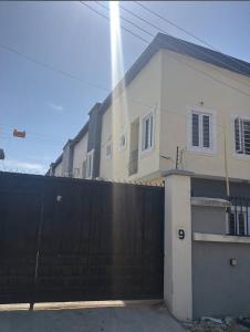 a white house with a black gate and a fence at Happy Lodge Shortlets & Suites, Freedom Way, Lekki phase 1 in Ogoyo