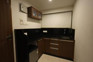 a small kitchen with wooden cabinets and a sink at MB hotel in Rajkot +21 photos