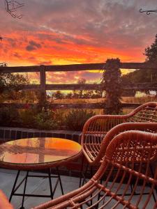 a patio with a table and chairs and a sunset at Room in the Nest in Bitchfield