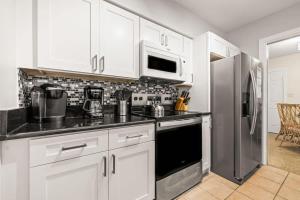 a kitchen with white cabinets and a stainless steel refrigerator at Sunset Beach House in Clearwater Beach