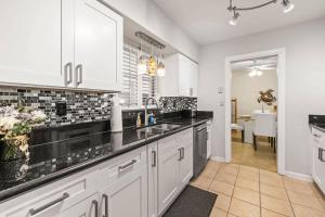 a kitchen with white cabinets and black counter tops at Sunset Beach House in Clearwater Beach +35 photos
