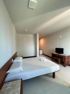 a bedroom with a bed and a desk with a laptop at Hotel Mata da Praia in Vitória