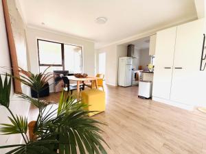 a living room with a table and a kitchen at The Bach at One Tree Point in One Tree Point +30 photos