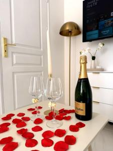a table with red roses and a bottle of wine at Studio Chic - Centre-Ville in Sablé-sur-Sarthe +4 photos