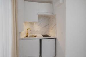 a kitchen with white cabinets and a sink at Studio Chic - Centre-Ville in Sablé-sur-Sarthe