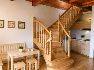 a wooden staircase in a living room with a table and a kitchen at Leśne Zacisze in Iława