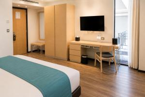 a hotel room with a bed and a desk with a television at Hotel Punto MX in Mexico City