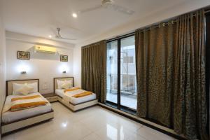 a bedroom with two beds and a large window at MB hotel in Rajkot