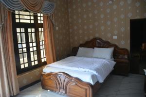 a wooden bed in a bedroom with two windows at Hotel Hills City, Swat in Mingāora
