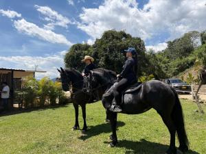 two people riding on horses in the grass at Payara Experience in La Vega
