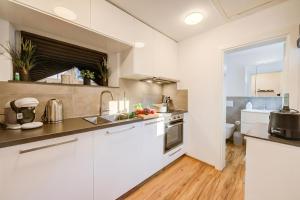 a kitchen with white cabinets and a sink at Casa Elvezia in Val Colla | Terrace + BBQ & Fireplace - Happy Rentals in Piandera