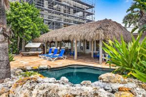 a swimming pool with chairs and a thatch hut at Gulf Front Dreams in Clearwater Beach