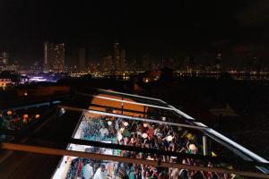a group of people standing on a balcony at night at Tantalo Hotel - Kitchen - Roofbar in Panama City