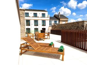 a balcony with wooden chairs and a building at Hotel Kavia Sarria in Sarria
