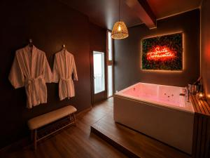 a bathroom with a tub and a sign on the wall at Evasion Terracotta - Jacuzzi privatif in Saint-Gaudens