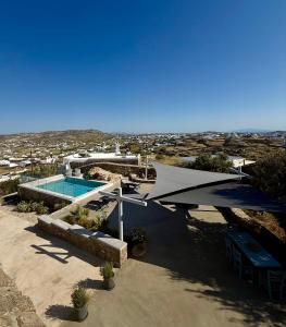 a house with a swimming pool and an umbrella at Villa Greystone & Sky Mykonos in Tourlos