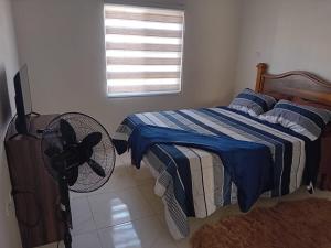 a bedroom with a bed with a fan and a window at Cozy Escape 876 Secure 2BR with AC, Parking & near Beaches in Portmore