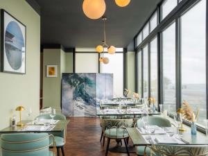 a restaurant with tables and chairs and large windows at Mercure Brighton Seafront Hotel in Brighton & Hove