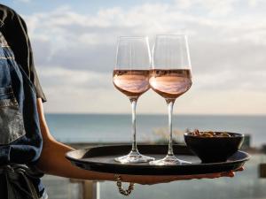 a person holding two glasses of wine on a tray at Mercure Brighton Seafront Hotel in Brighton & Hove
