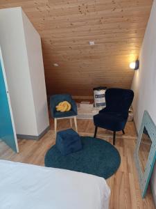 a bedroom with two chairs and a bed and a table at Soleil Bleu in Saint-Racho