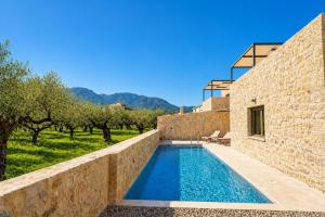 a swimming pool next to a stone building with trees at Villa Castillo Thio in Agios Nikolaos