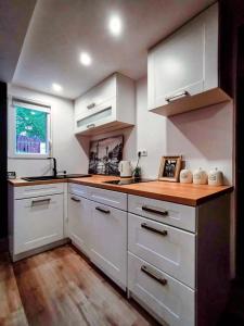 a kitchen with white cabinets and a wooden floor at Hegyi Kuckó Vendégház - Forest Hideaway with Jacuzzi in Biatorbágy