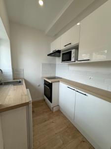 a kitchen with white cabinets and a microwave at Appartements Agde Cap d Agde in Agde