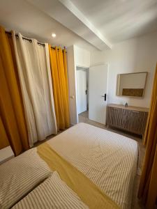 two beds in a room with yellow curtains at Appartements Agde Cap d Agde in Agde +6 photos