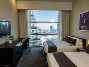 a hotel room with two beds and a large window at Stadia Suites Mexico City Santa Fe in Mexico City
