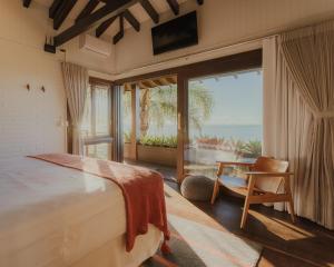 a bedroom with a bed and a view of the ocean at Villa Gardena Suites in Praia do Rosa