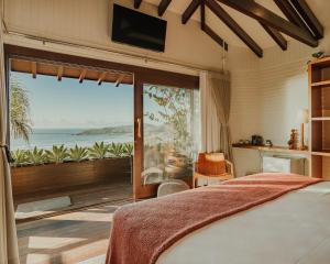 a bedroom with a bed and a view of the ocean at Villa Gardena Suites in Praia do Rosa